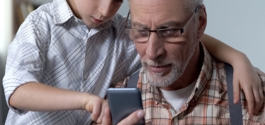 Abuelo y nieto mirando móvil.