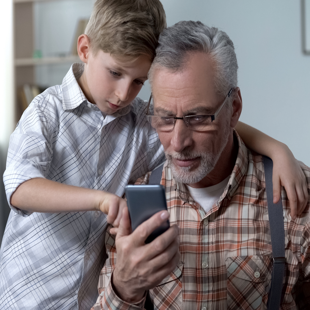 Abuelo y nieto mirando móvil.